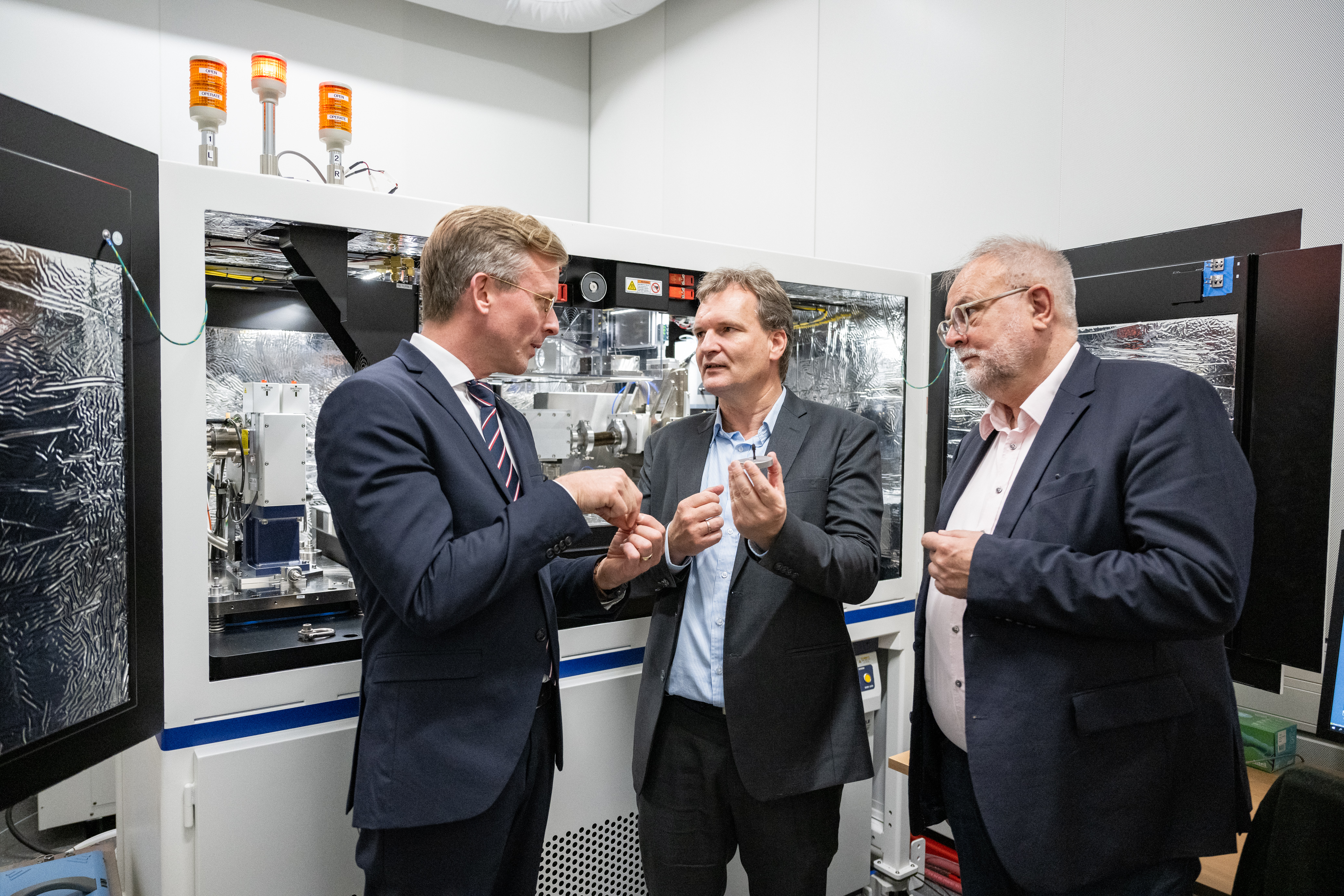 Staatssekretär Dr. Dirk Günnewig, Professor Dirk Sauer und RWTH-Kanzler Manfred Nettekoven stehen vor Batterietechnik.