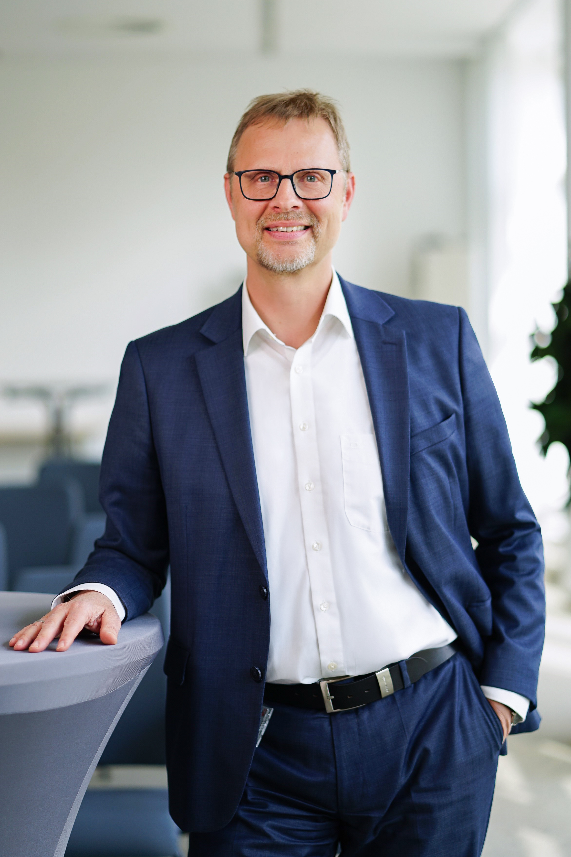 Abteilungsleiter am Stehtisch schaut in die Kamera