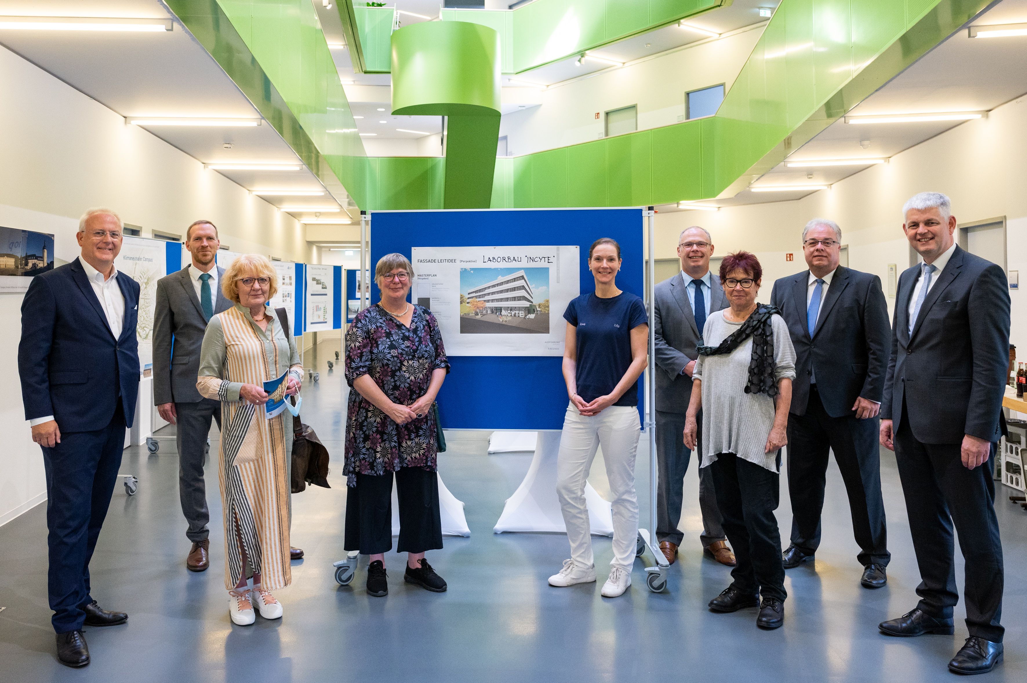 Gruppenfoto des Verwaltungsrats des BLB mit dem Kanzler der Universotät vor der Fotowand des INCYTE-Forschungsbaus.