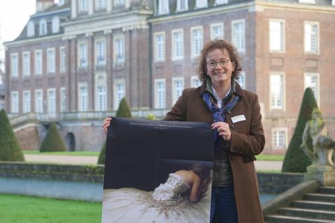 Dr. Birgit Beisch vor dem Schloss Nordkirchen mit dem Plakat zur Spencer-Schlossführung.