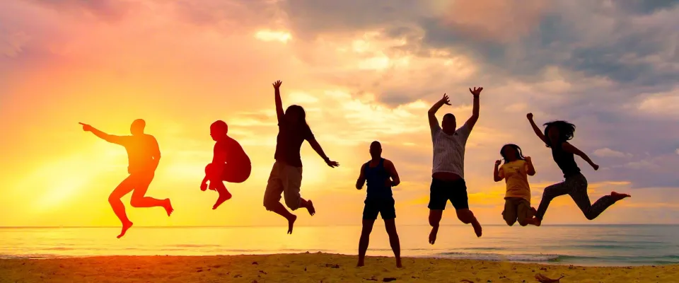 Gruppe Menschen am Strand springen in die Luft