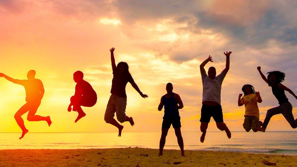 Gruppe Menschen am Strand springen in die Luft
