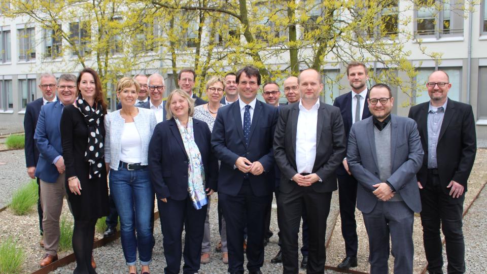 Minister Dr. Marcus Optendrenk (1. Reihe, 3.v.r.) wird von der Dienstellenleitung Dr. Thomas Flögel (1.Reihe, 2.v.r.) und seinem Team des Finanzamts für Groß- und Konzernbetriebsprüfung Mönchengladbach herzlich begrüßt.
