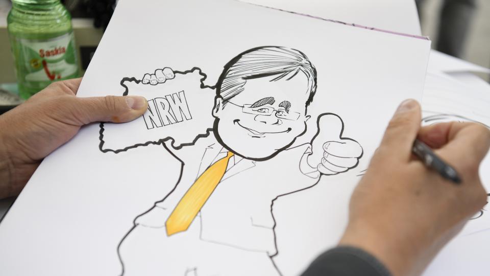 Zeichnung von Armin Laschet mit dem Land NRW in der einen Hand und einem Daumen nach oben