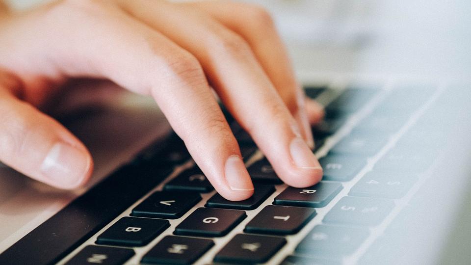 Laptop-Tastatur mit menschlicher Hand
