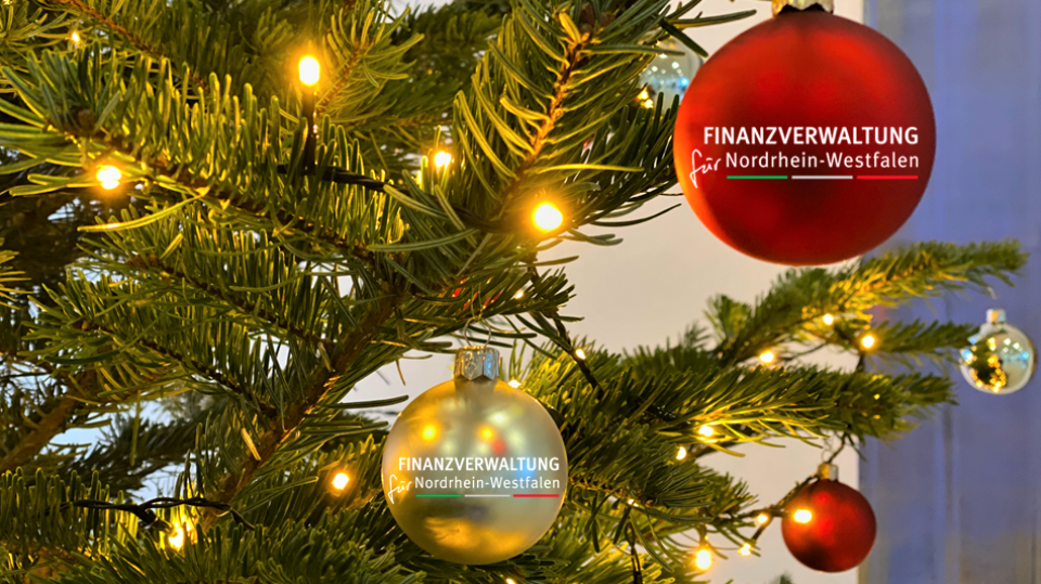 An einem Weihnachtsbaum hängen Weihnachtskugeln mit der Aufschrift "Finanzverwaltung für Nordrhein-Westfalen".