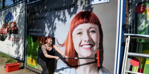 Victoria G. vom Finanzamt Düsseldorf-Süd, eines der "Gesichter" der Kampagne, klebt das erste Plakat.